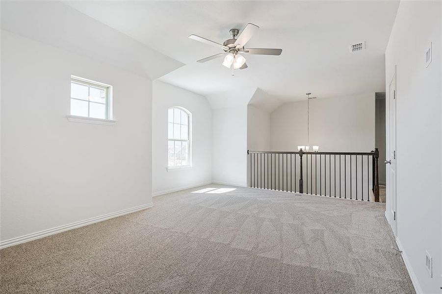 Spare room with ceiling fan with notable chandelier, vaulted ceiling, and carpet floors