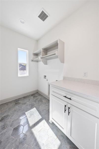 Washroom featuring hookup for a washing machine, cabinet space, and light stone finish flooring