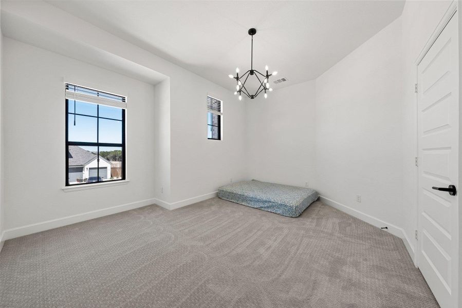 Unfurnished bedroom featuring a chandelier, carpet flooring, visible vents, and baseboards