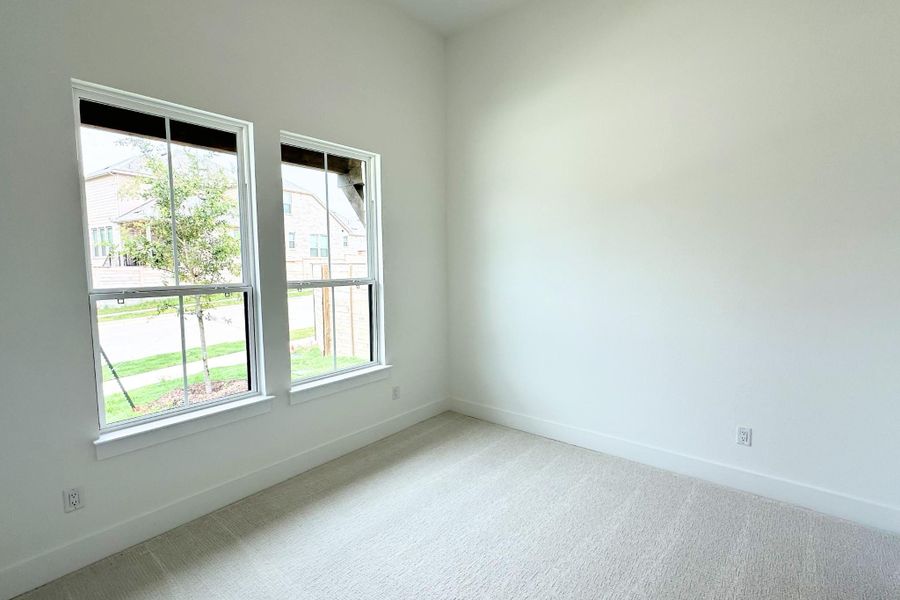 Two generous windows bathe this spacious bedroom in natural illumination, creating an airy ambiance.