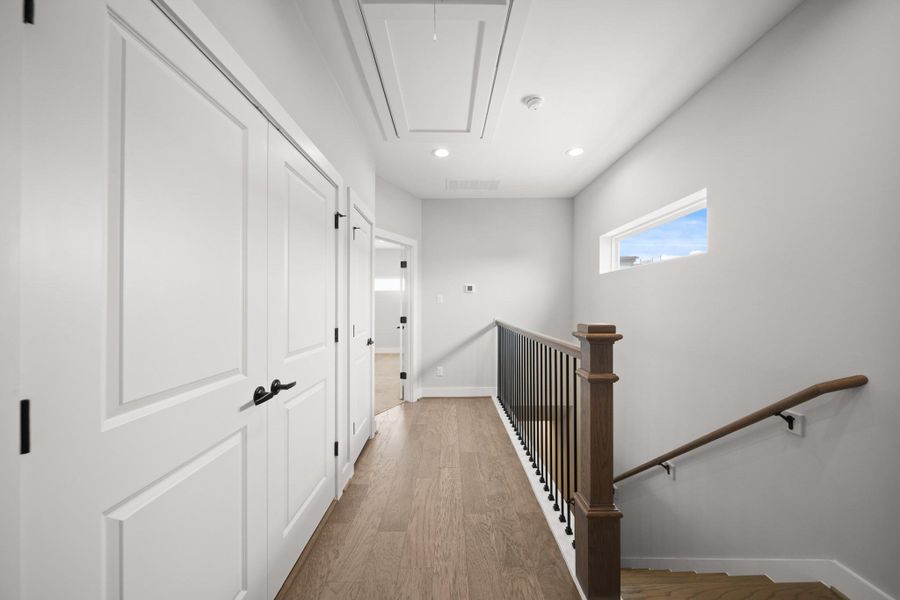 A view of the third floor landing with the laundry room on the left and the primary bedroom straight ahead. A view of the third floor landing with the laundry room on the left and the primary bedroom straight ahead.
