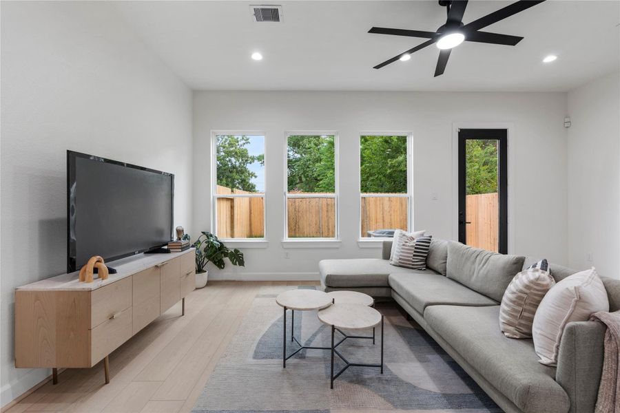 Living room framed by tall windows for abundant natural light and backyard views. Living room framed by tall windows for abundant natural light and backyard views.