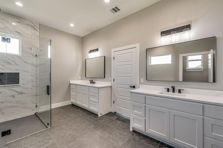 Bathroom featuring tile patterned flooring, a shower with shower door, and vanity