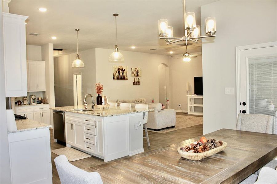 Kitchen with arched walkways, white cabinetry, light wood-style floors, light stone counters, and open floor plan Kitchen with arched walkways, white cabinetry, light wood-style floors, light stone counters, and open floor plan