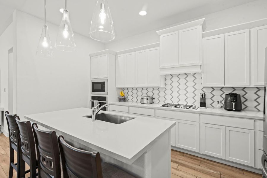 This stunning kitchen seamlessly blends contemporary design with exceptional functionality. Upgraded features include deep drawers for pots and pans and a pull-out trash/recycle drawer, enhancing both convenience and clean lines. Sleek wood cabinetry and polished quartz countertops create a timeless aesthetic, accented by a stylish glass tile backsplash. A large walk-in pantry ensures ample storage, making the space equally suited for culinary enthusiasts and refined entertaining.