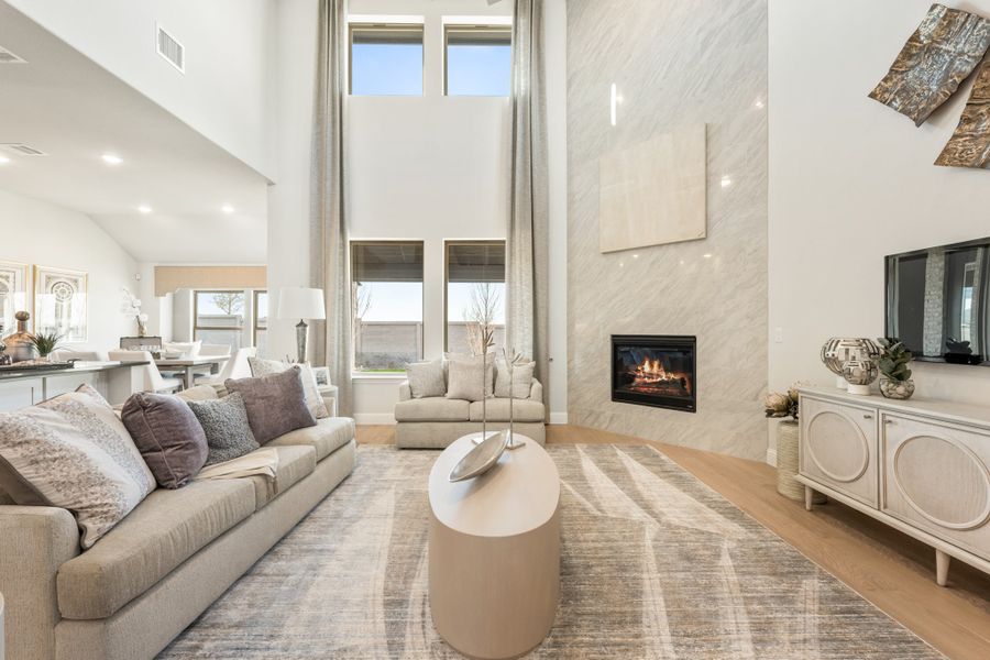 Open living room with two-story ceilings, stone fireplace, and hardwood floors
