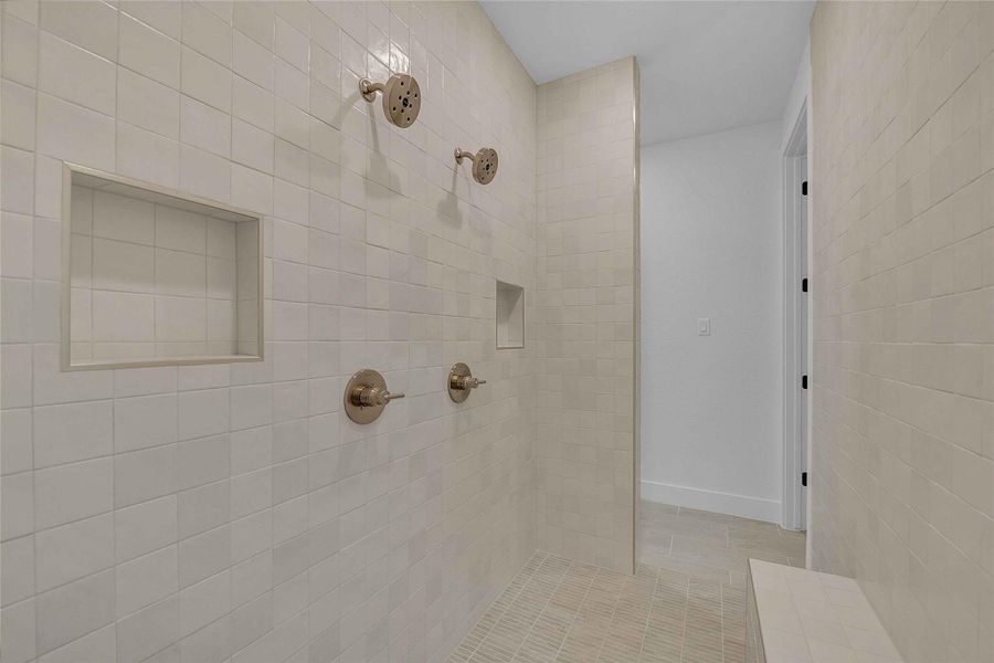 Bathroom with baseboards, tile patterned flooring, and a tile shower Bathroom with baseboards, tile patterned flooring, and a tile shower