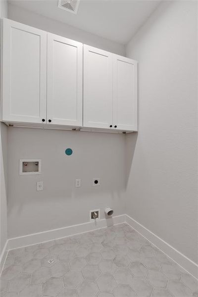 The laundry room pairs functionality with aesthetic delight, featuring hexagon tile flooring and thoughtfully placed cabinets.