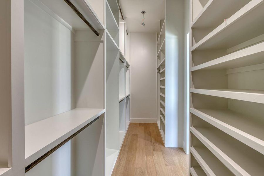 Custom built-in shelving and smooth wood flooring maximize storage in this walk-in closet.