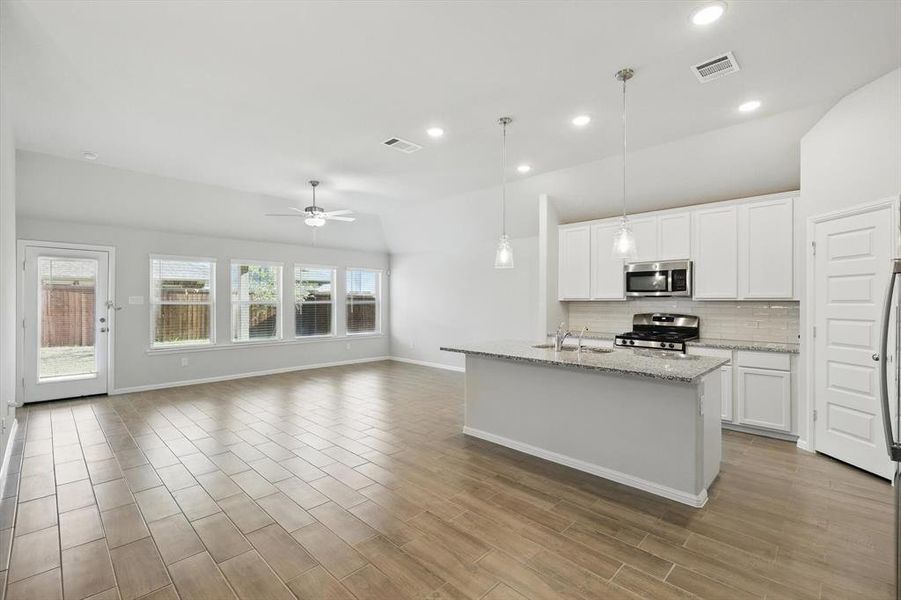 Kitchen featuring appliances with stainless steel finishes, tasteful backsplash, a ceiling fan, white cabinetry, and lofted ceiling Kitchen featuring appliances with stainless steel finishes, tasteful backsplash, a ceiling fan, white cabinetry, and lofted ceiling