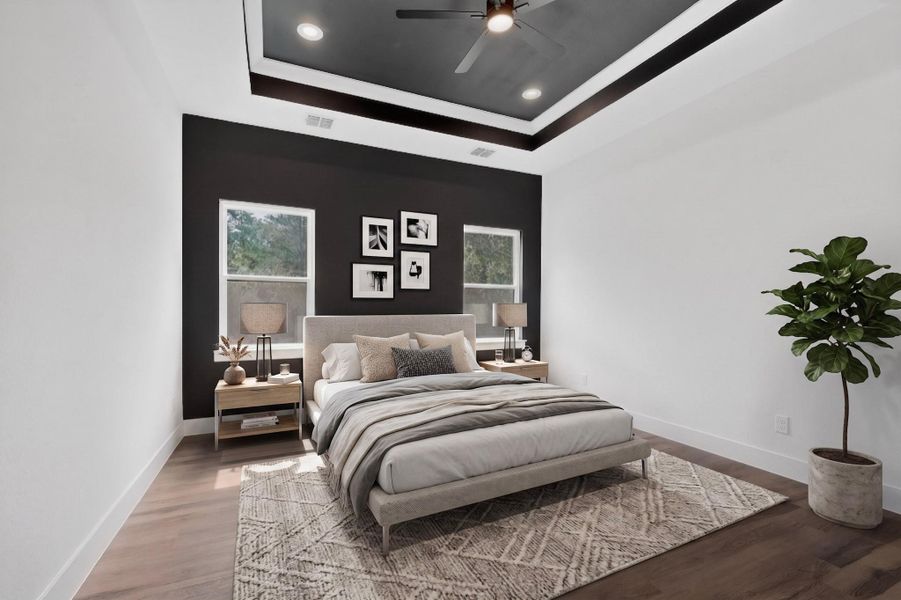 Modern design meets comfort in this inviting sleeping space, featuring rich wood flooring and a distinctive tray ceiling.