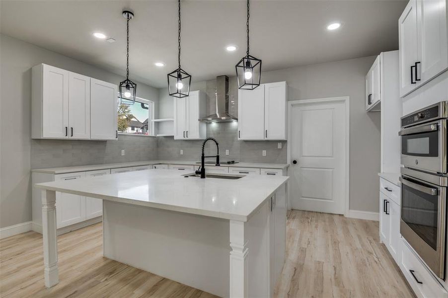 Kitchen featuring double oven, hanging light fixtures, light wood-style flooring, tasteful backsplash, and recessed lighting Kitchen featuring double oven, hanging light fixtures, light wood-style flooring, tasteful backsplash, and recessed lighting