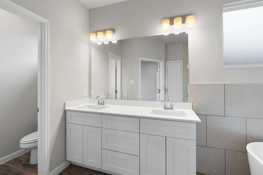 Double vanity with pristine countertops and integrated sinks elevate this well-appointed bathroom.