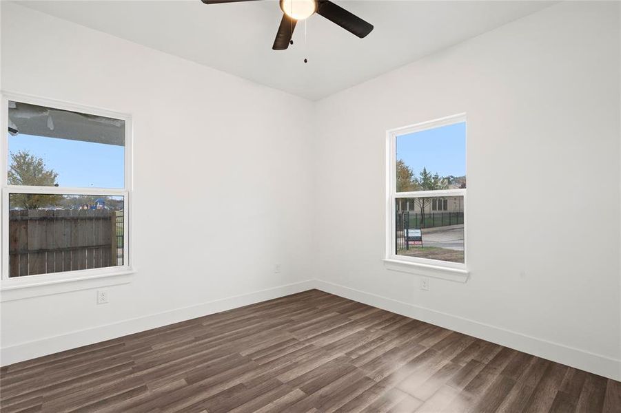 Empty room featuring ceiling fan and dark hardwood / wood-style flooring