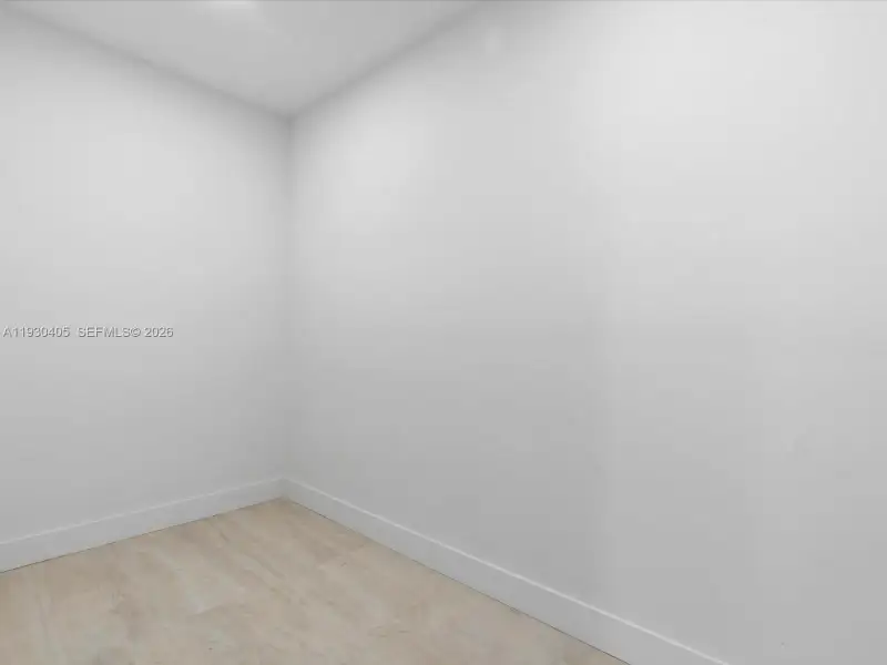 Neutral-toned interior space featuring smooth white walls and wood-finish flooring Neutral-toned interior space featuring smooth white walls and wood-finish flooring