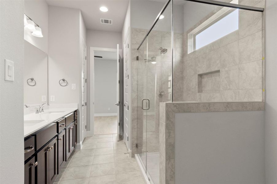 Bathroom with double vanity, a shower stall, and tile patterned flooring