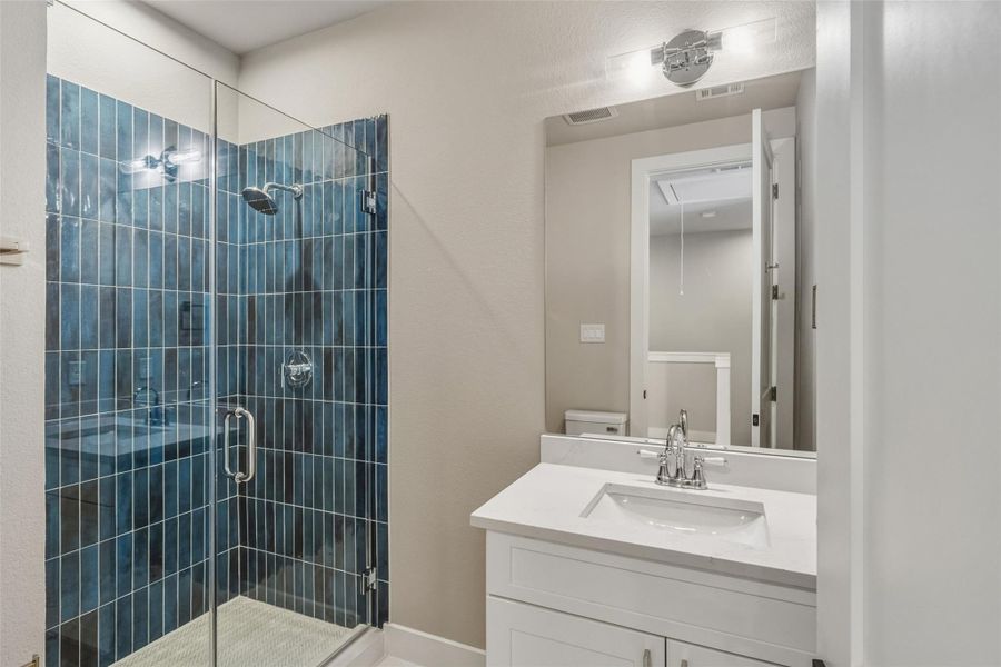 This inviting secondary bathroom features a stunningly tiled shower, offering both style and comfort.
