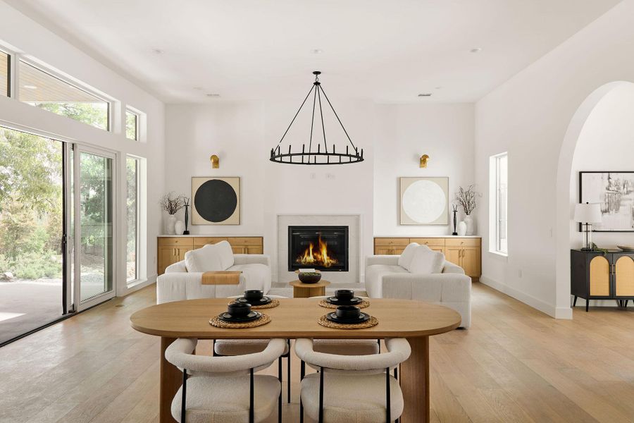 Dining room featuring light wood-type flooring, a high ceiling, a glass covered fireplace, plenty of natural light, and arched walkways Dining room featuring light wood-type flooring, a high ceiling, a glass covered fireplace, plenty of natural light, and arched walkways
