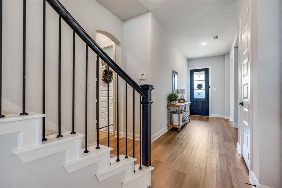 Foyer with light wood-style floors, arched walkways, and stairs