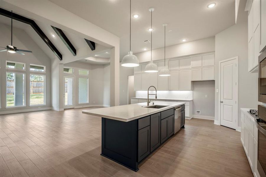 Step into this stunning open-concept kitchen and living area, where sloped ceilings adorned with elegant wood beams and expansive windows invite natural light to dance throughout.