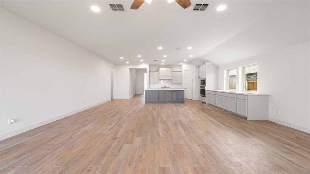 Unfurnished living room featuring light wood-type flooring and ceiling fan