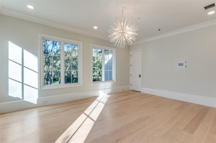 Unfurnished room with light hardwood / wood-style floors, crown molding, and an inviting chandelier