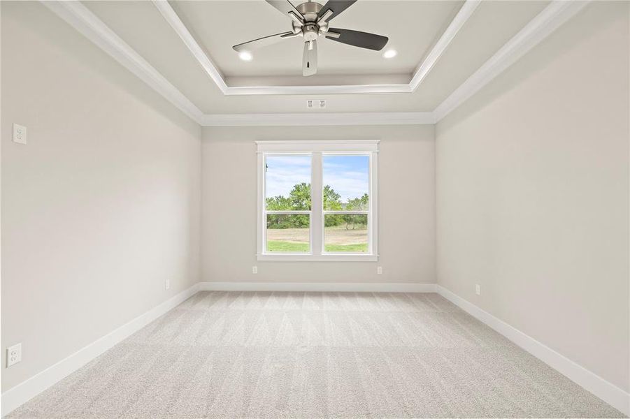 Empty room featuring light colored carpet, recessed lighting, ceiling fan, ornamental molding, and a tray ceiling Empty room featuring light colored carpet, recessed lighting, ceiling fan, ornamental molding, and a tray ceiling