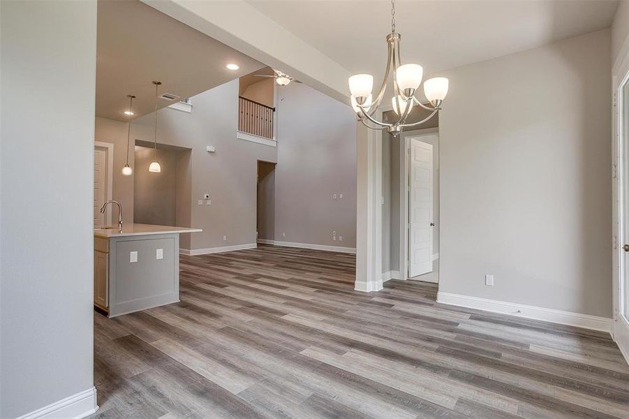 Unfurnished living room with a high ceiling, sink, ceiling fan with notable chandelier, and hardwood / wood-style floors