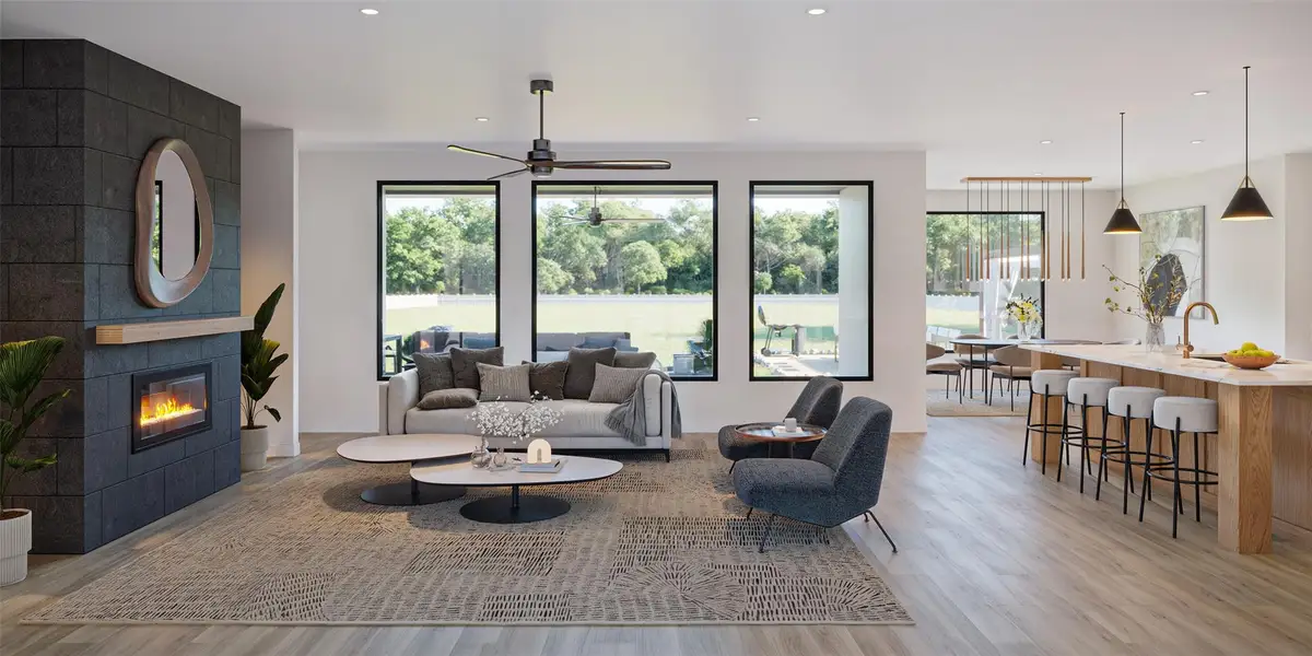 An open concept living area boasts a sleek fireplace, large windows overlooking lush greenery, and a bright kitchen island. An open concept living area boasts a sleek fireplace, large windows overlooking lush greenery, and a bright kitchen island.