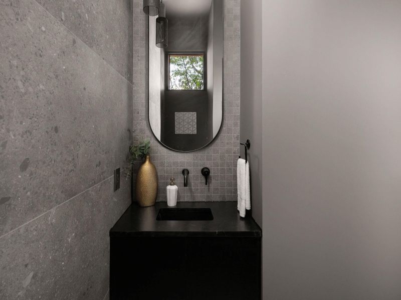 A minimalist powder room pairs sleek dark stone countertops with textured gray tiling.
