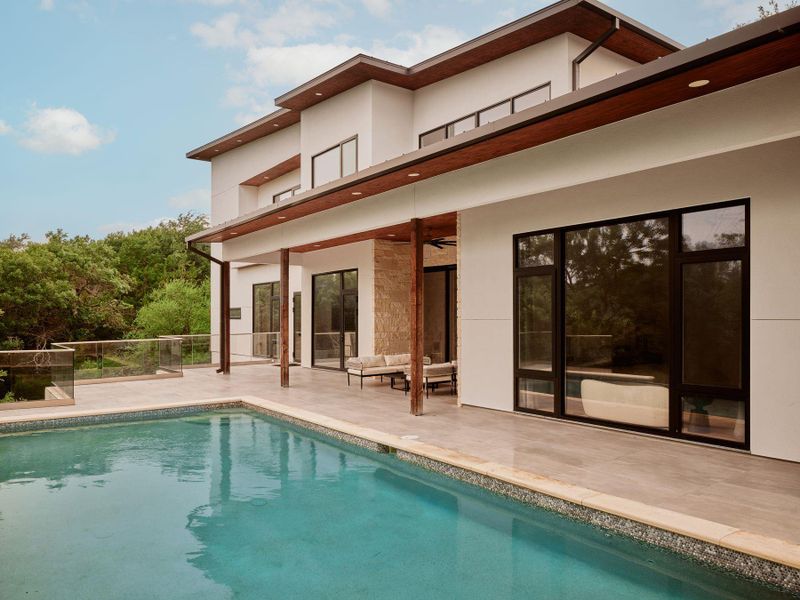 An inviting pool alongside a modern home with extensive glass and natural wood accents. An inviting pool alongside a modern home with extensive glass and natural wood accents.