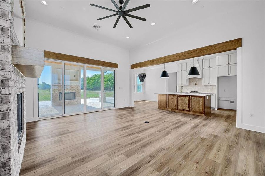 Unfurnished living room with ceiling fan, a fireplace, and light hardwood / wood-style flooring