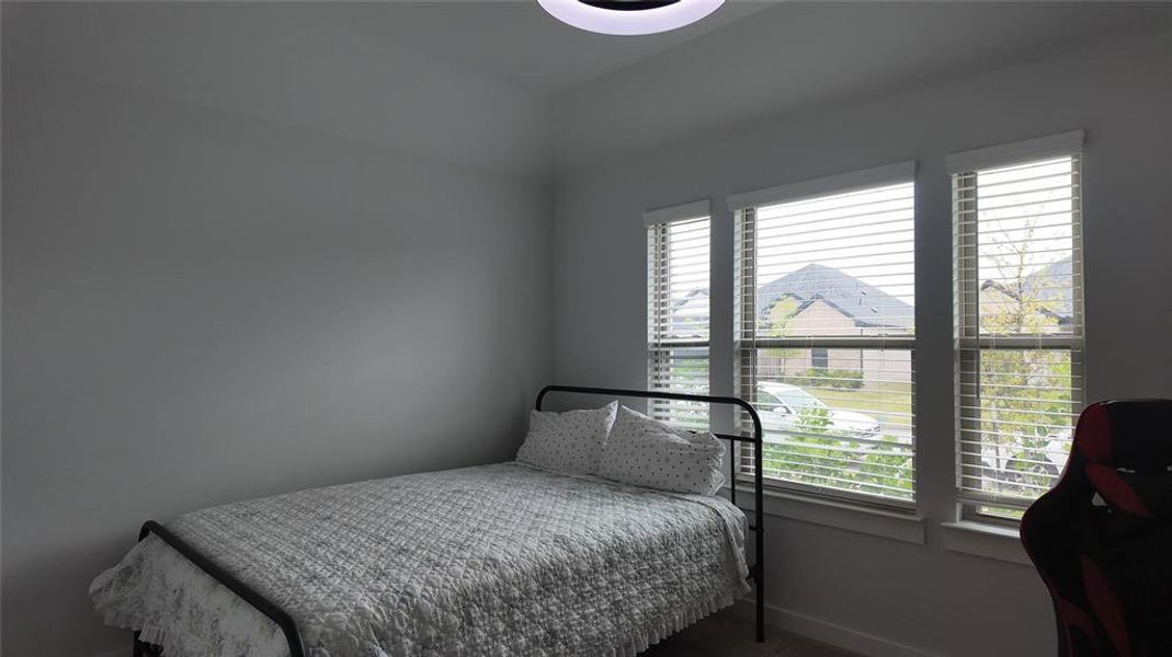 This room features light gray walls and three windows with white blinds, providing natural light