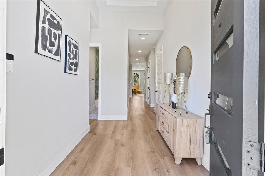 Corridor featuring light wood-type flooring, visible vents, baseboards, and recessed lighting