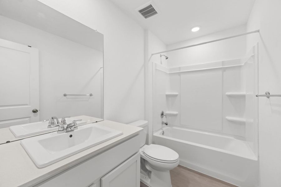 Bathroom features a spacious vanity, large wall mirror, and tub/shower combination with built-in shelving. Bathroom features a spacious vanity, large wall mirror, and tub/shower combination with built-in shelving.