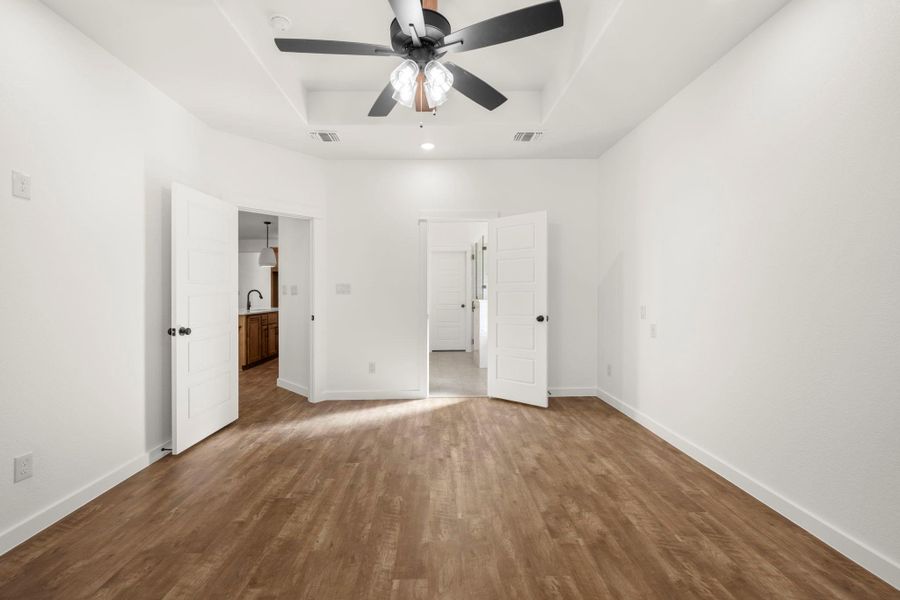 An inviting room boasts a tray ceiling and wood-look flooring, ready for personalization.