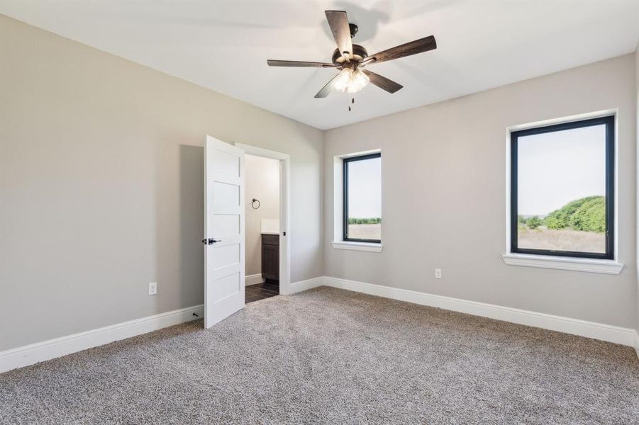 Bedroom featuring ensuite bath, baseboards, carpet, and a ceiling fan Bedroom featuring ensuite bath, baseboards, carpet, and a ceiling fan