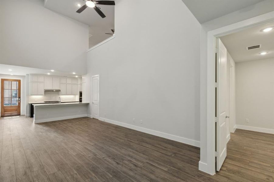 Unfurnished living room with dark wood-style flooring, ceiling fan, and baseboards