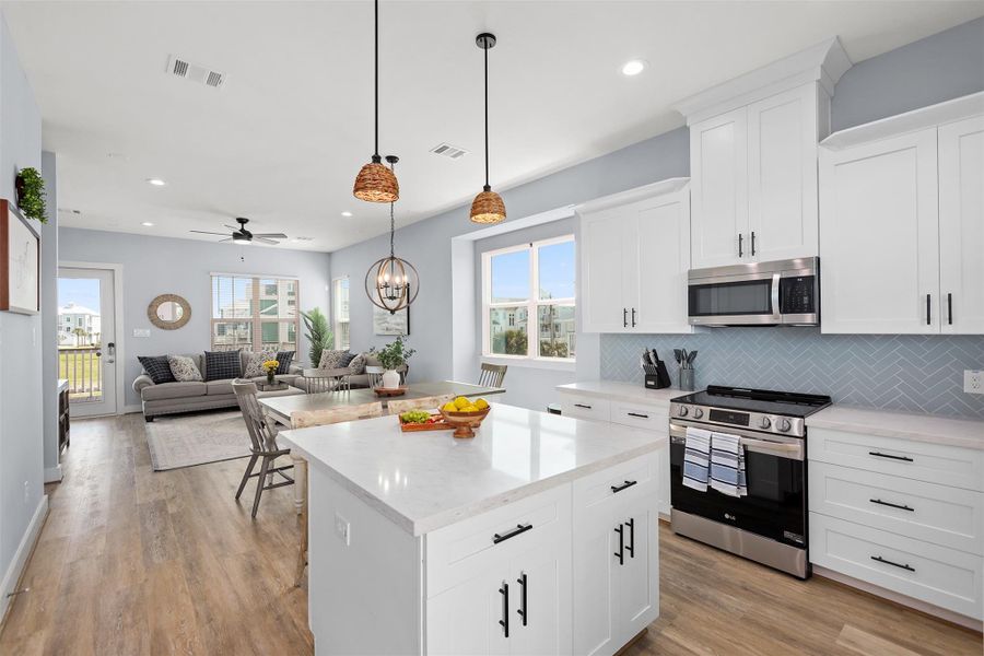 A closer look at the kitchen highlights the oversized island with seating, sleek granite counters, and stainless steel appliances that make both cooking and entertaining a joy.