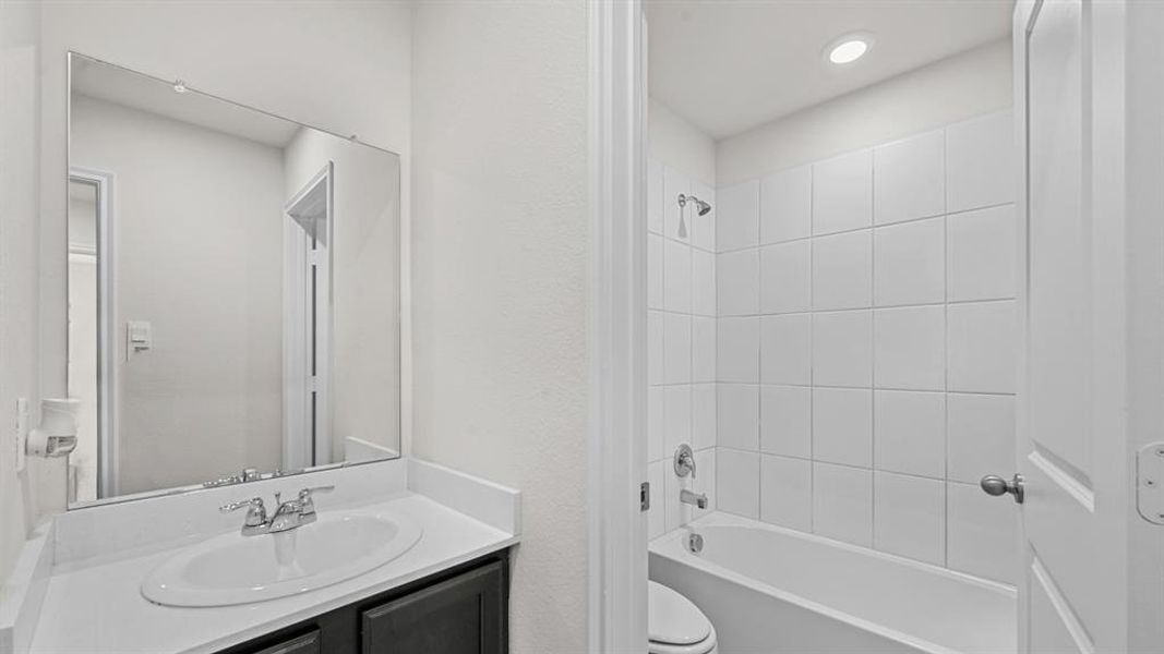 Bathroom featuring a white vanity countertop, undermount sink, and dark wood-finish cabinetry