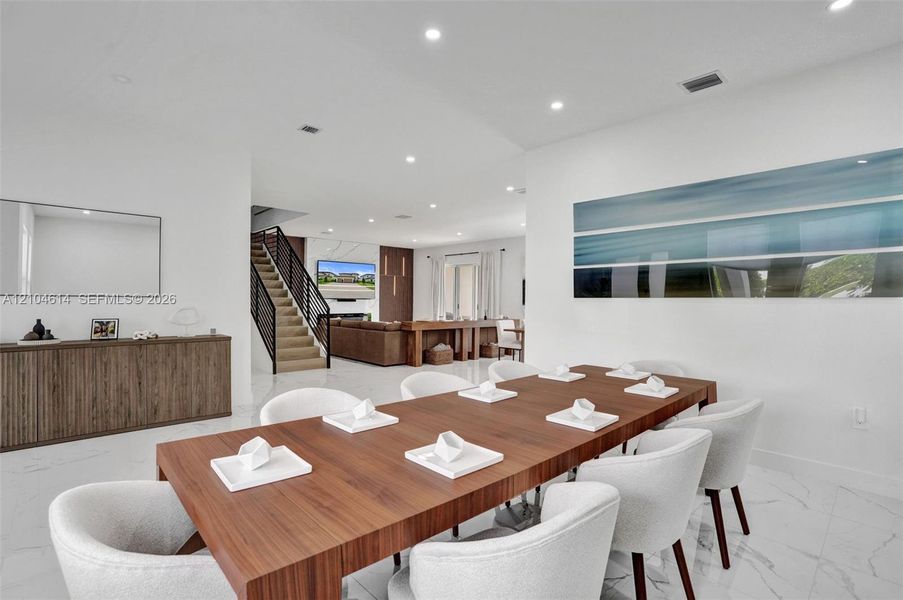 Spacious open-concept living area, recessed lighting, and white flooring