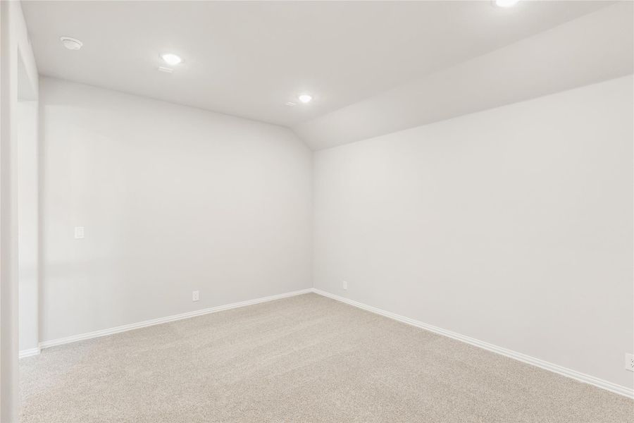 Empty room with white walls, beige carpet, recessed lighting, and vaulted ceiling