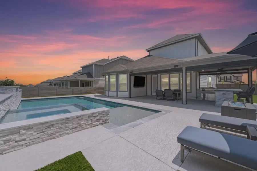 In-ground swimming pool with integrated spa and stacked stone surround