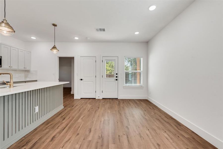 Kitchen with pendant lighting, recessed lighting, light wood-style floors, backsplash, and white cabinets Kitchen with pendant lighting, recessed lighting, light wood-style floors, backsplash, and white cabinets