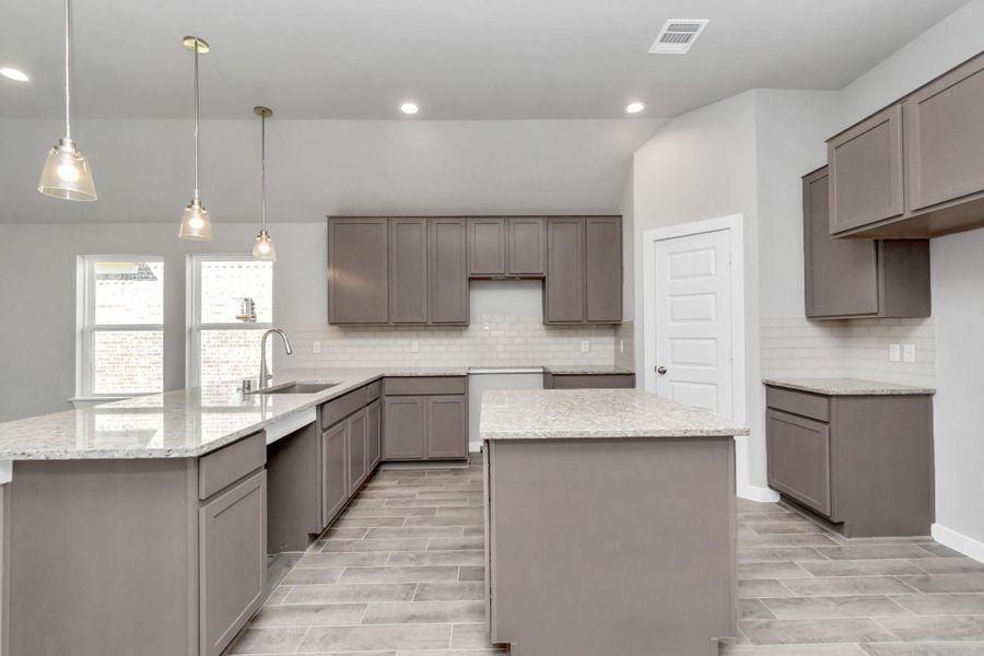 Discover another perspective of this stunning kitchen, generously appointed with an abundance of counter space. Sample photo of completed plan. As-built color and selections may vary. Discover another perspective of this stunning kitchen, generously appointed with an abundance of counter space. Sample photo of completed plan. As-built color and selections may vary.