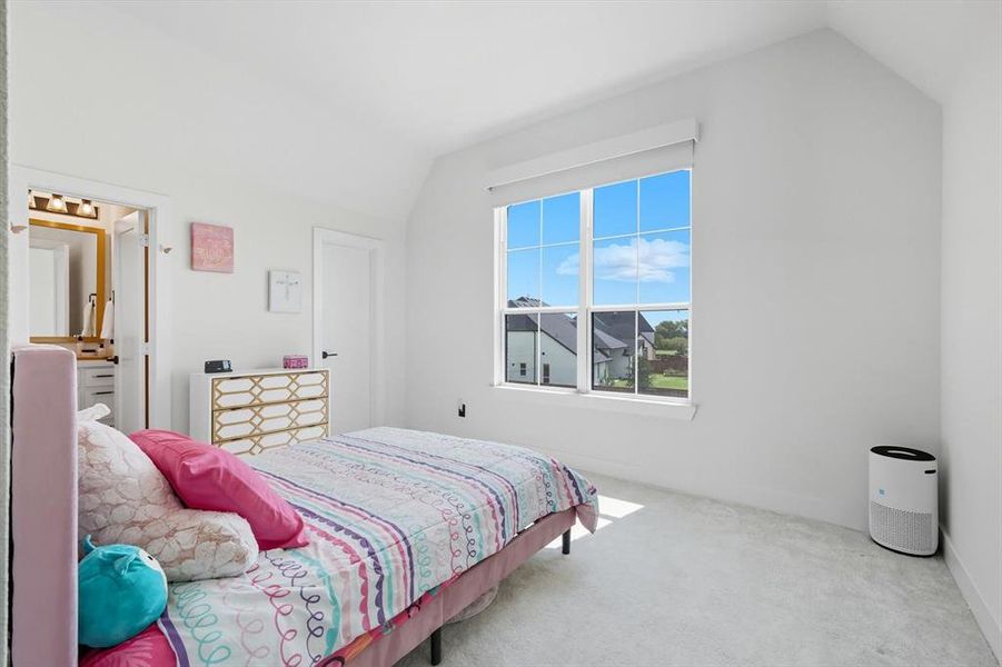 Upstairs carpeted bedroom featuring lofted ceiling, ensuite bathroom & walk-in closet Upstairs carpeted bedroom featuring lofted ceiling, ensuite bathroom & walk-in closet