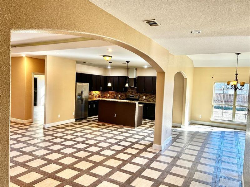 Kitchen with stainless steel refrigerator with ice dispenser, tasteful backsplash, pendant lighting, a notable chandelier, and a center island