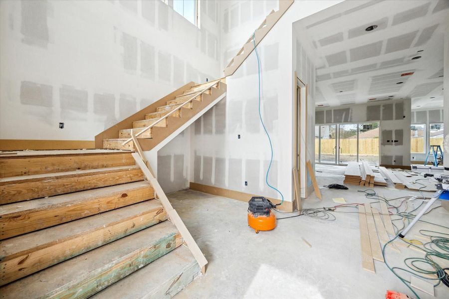 The main entry opens with a striking open staircase and generous ceiling height, creating a sense of volume and architectural presence from the moment you arrive. Clear sightlines extend toward the main living areas and backyard, while the layout allows for a statement wine wall with storage tucked beneath the stairs and seamless flow into the heart of the home.