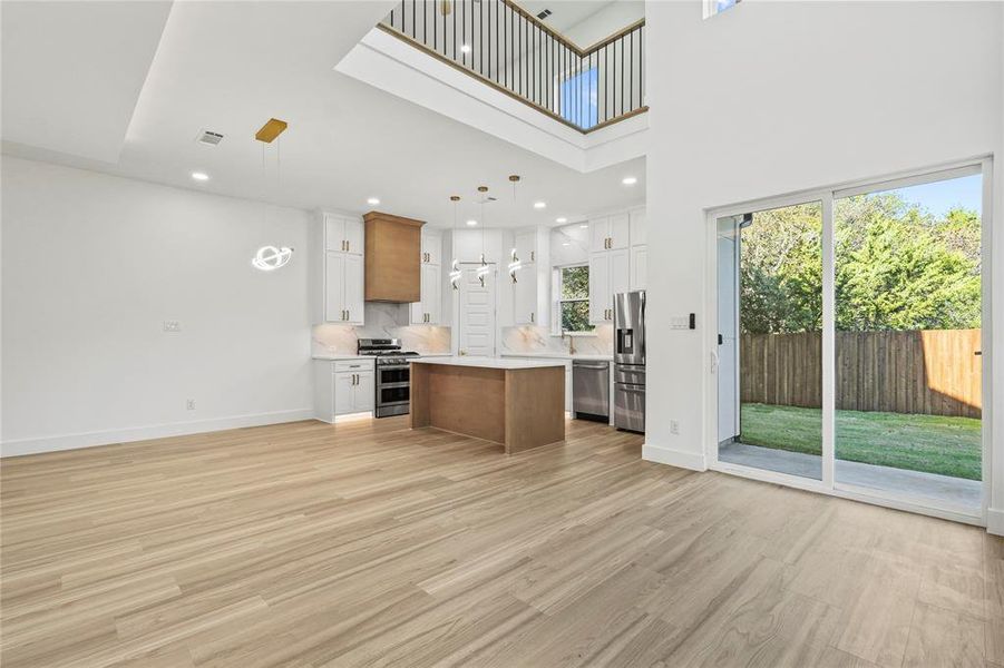 Kitchen featuring open floor plan, brown cabinets, a kitchen island, light wood-style flooring, and decorative backsplash