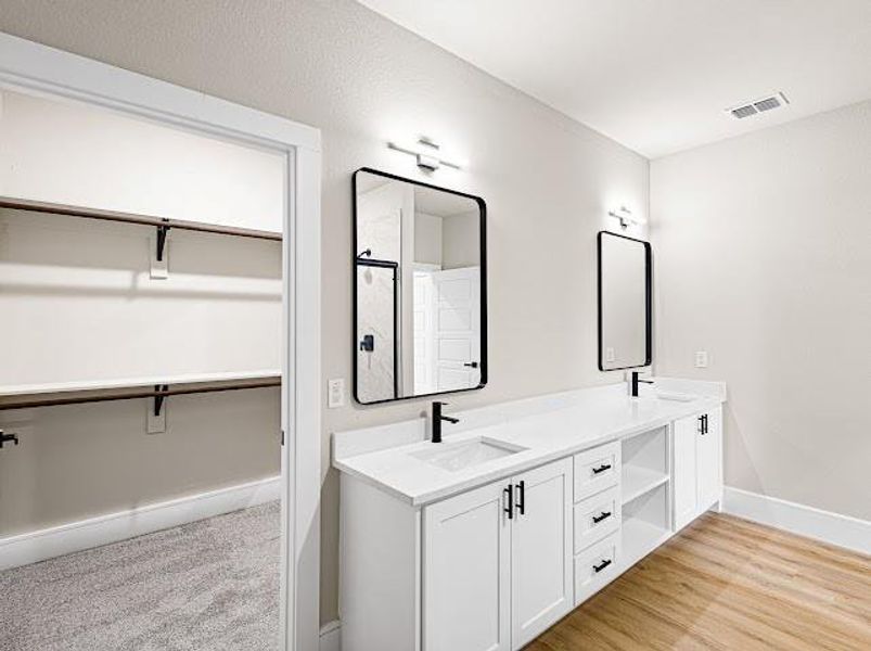 Full bath with a walk in closet, double vanity, and light wood-type flooring Full bath with a walk in closet, double vanity, and light wood-type flooring